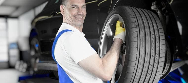 Mechaniker trägt einen neuen Reifen in der Werkstatt